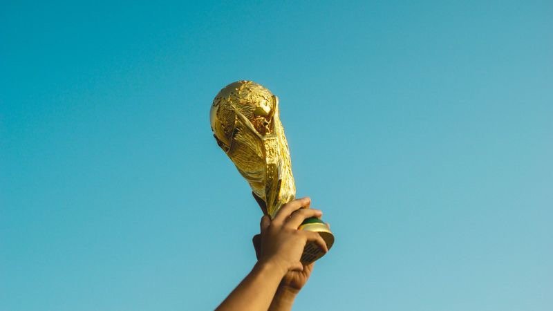 Der Fussball WM Pokal wird in die Höhe gereckt.